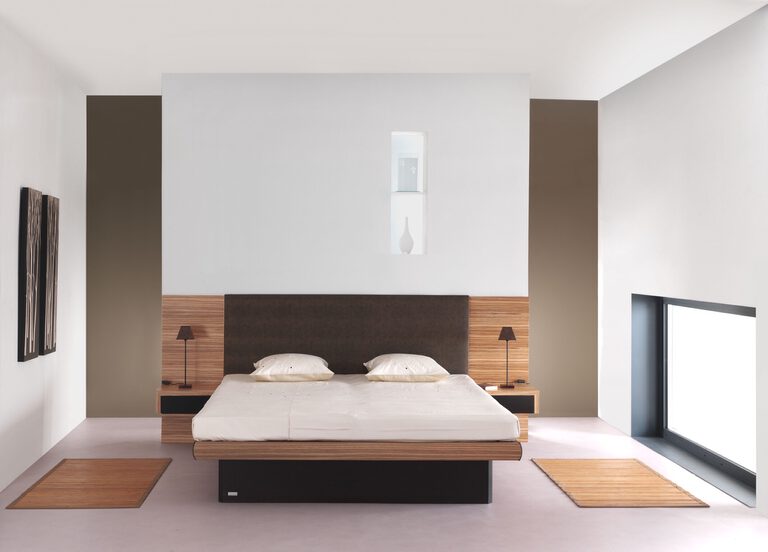 Bett mit Kopfteil aus Holz, eingebauten Nachttischen und Leuchten in einem hellen Schlafzimmer