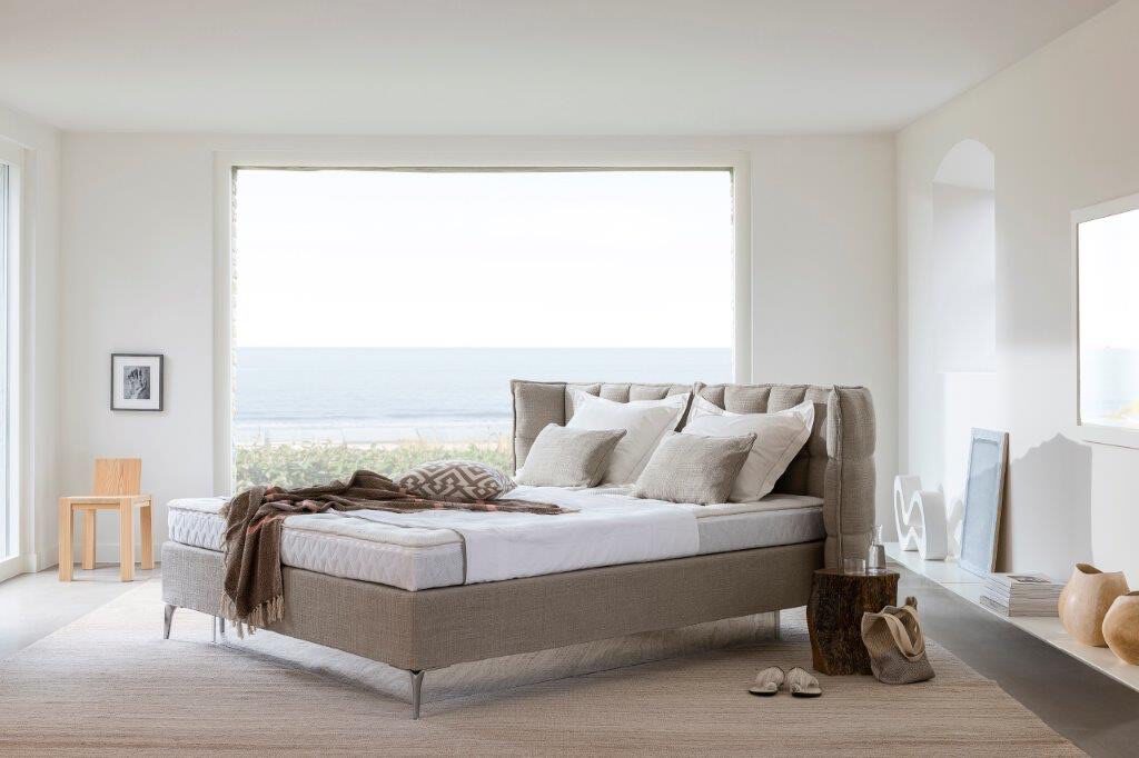 Helles Schlafzimmer mit Meerblick und gepolstertem Bett mit gestepptem Kopfteil
