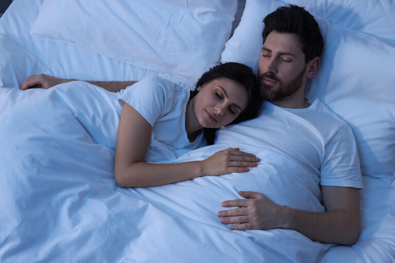 Paar schläft eng beieinander in einem Bett